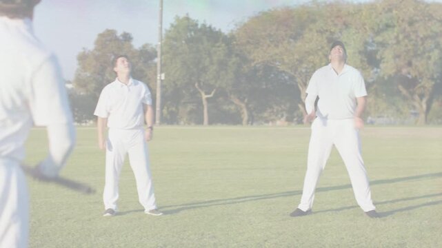 Cricket batsman swinging bat sending ball up, fielders tracking, tall fielder catching for wicket