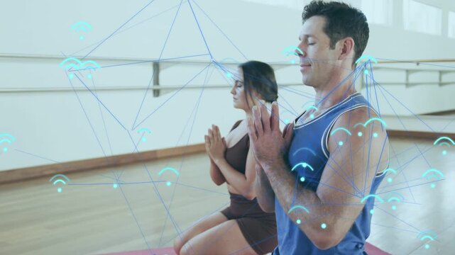 Man and woman bringing palms together on mats, blue WiFi overlay linking meditation to centering