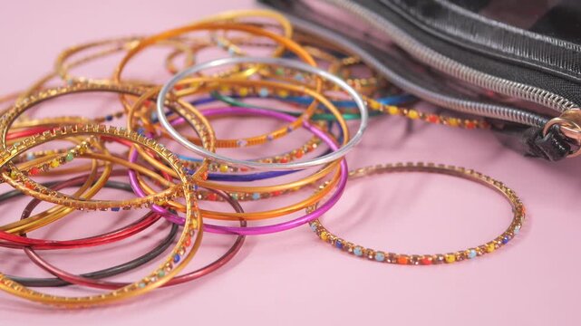 Colorful bangles and purse on pink background