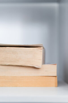 stack of old books on minimalist white bookshelf shallow depth of field