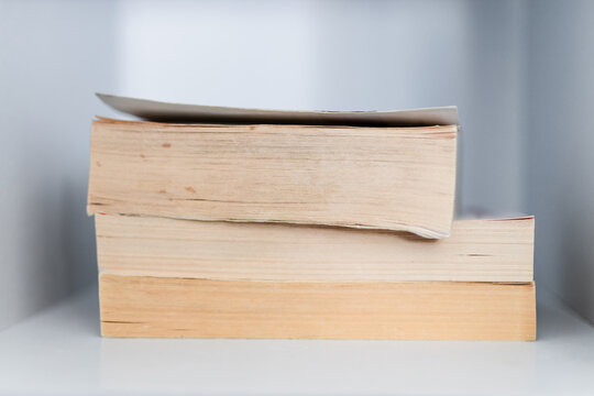 stack of old books on minimalist white bookshelf shallow depth of field