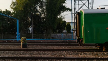 Rear train carriage standing on railway tracks at a station with industrial surroundings, ideal for transportation themes, logistics visuals, travel content, and infrastructure-related design. © M MUSHTHOFA MAHFUD