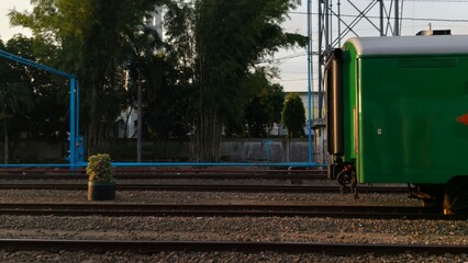 Rear train carriage standing on railway tracks at a station with industrial surroundings, ideal for transportation themes, logistics visuals, travel content, and infrastructure-related design. © M MUSHTHOFA MAHFUD