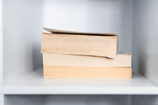 stack of old books on minimalist white bookshelf shallow depth of field