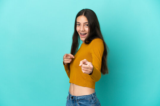 Young French woman isolated on blue background surprised and pointing front