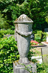 schöne sehr alte Urne aus Stein mit einem Kranz  auf einem Friedhof in Köln © Blende8