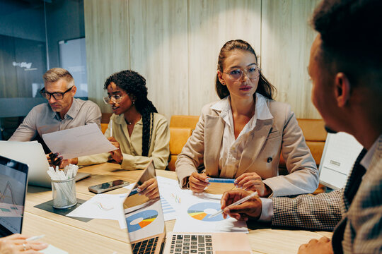 Multiracial team negotiating project details in meeting