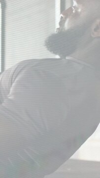 Vertical video: Starting leaned-back, bearded man pulling and rotating torso right for exercise