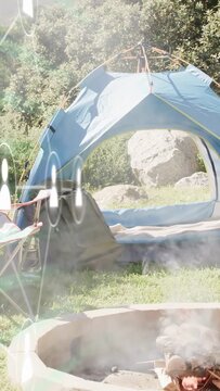 Vertical video: Tilting camera, blue tent showing pad, smoke drifting and sun glares revealing camp