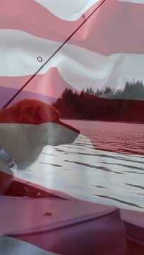 Vertical video: Dog riding boat bow moving on lake, flag waving and dog scanning shore for travel