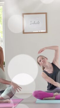Vertical video: Right teen copying left reach, deepening yoga stretch, breathing, with bokeh effect