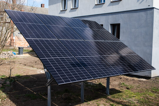 Modern photovoltaic solar panel installation on a ground mount in a residential backyard for renewable energy.