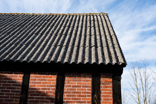 Close-up of old corrugated asbestos roof sheets, also known as eternit, on an old brick and wood building.