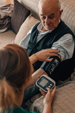 healthcare professional in uniform and wearing a stethoscope takes an elderly person's blood pressure in their home, conveying trust, care, and compassionate medical assistance
