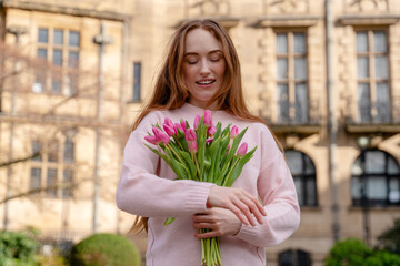 Fototapeta premium Woman holding pink tulips in front of a building during the day 