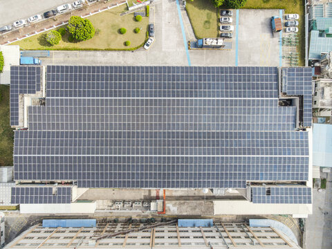 Aerial view of a large industrial building roof covered with a vast array of solar panels under bright daylight Dongguan, Guangdong Province, China.
