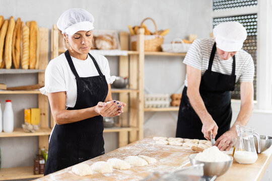 Elderly man and woman cutting dough and forming pieces