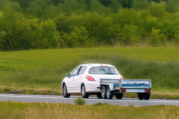 Fototapeta premium Car towing transport trailer along scenic country road