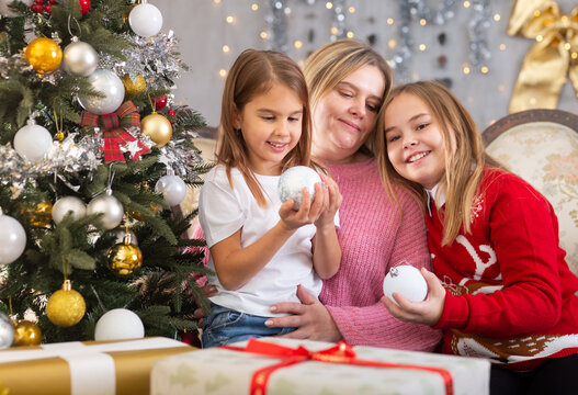 Mom with two daughters hugging in Christmas interior