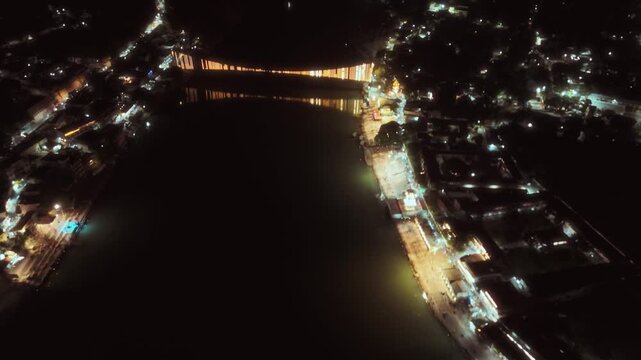 Cinematic view of Rishikesh at night glowing with lights along the Ganga river, showcasing peaceful and spiritual beauty.