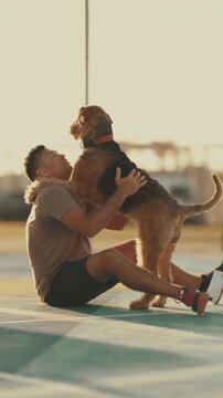 Happy man playing with airedale terrier dog outdoors