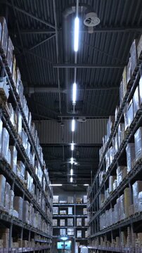 Industrial warehouse interior with long aisles, high racks, and shelves stacked with cardboard boxes and packages, ready for shipment and distribution in a modern logistic center