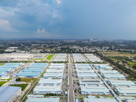 Aerial view of a large industrial park with rows of blue-roofed warehouses and organized streets under a cloudy sky in An Phuoc, Dong Nai, Vietnam.