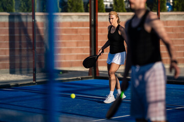 Fototapeta premium Woman playing padel on blue court with racket