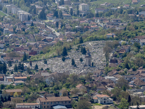 High-angle aerial view of the Heroes' Cemetery in Deva, Romania, featuring a dense arrangement of white monuments and the chapel tower