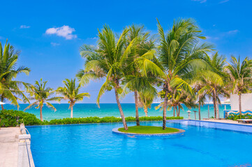 Obraz premium landscape with an infinity swimming pool on beach with palm trees by the sea in luxury hotel in a resort in tropics in Asia in summer