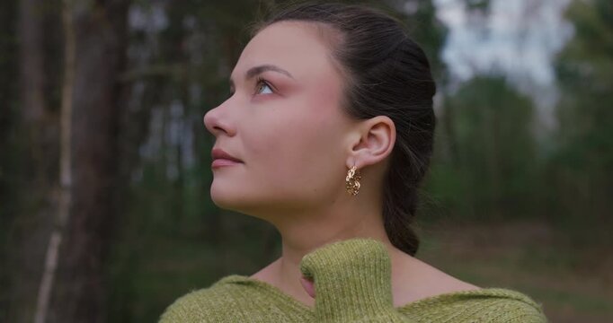 Closeup elegant girl with gold earring enjoying nature in slow motion