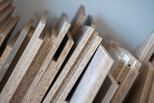 Stack of particle board panels in workshop, chipboard sheets for furniture production, wood material background with shallow depth of field
