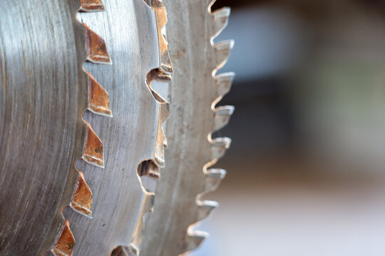 Close-up of circular saw blades with sharp teeth. Industrial metal cutting tools used in woodworking, construction and manufacturing. Detailed texture with shallow depth of field.