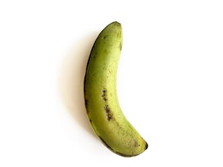 Single green plantain banana with natural dark spots on peel, isolated on white background. Tropical fruit for cooking, baking, traditional cuisine, and herbal medicine concepts. © FaizZakiy