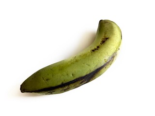 Single green plantain banana with natural dark spots on peel, isolated on white background. Tropical fruit for cooking, baking, traditional cuisine, and herbal medicine concepts. © FaizZakiy