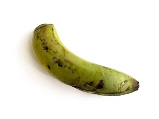 Single green plantain banana with natural dark spots on peel, isolated on white background. Tropical fruit for cooking, baking, traditional cuisine, and herbal medicine concepts. © FaizZakiy