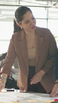 Vertical video: Leaning lead in blazer pointing opening marker, moving notes at office leading team