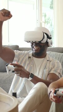 Smiling man in striped shirt with VR headset on couch after game start using controller celebrating