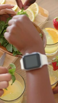 Vertical video: Moving mint bowl in frame, hands adding mint to drinks at table to present