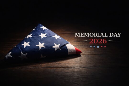 Memorial Day 2026 tribute with folded American flag and golden light on dark wooden background