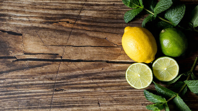 Lemon and lime slices with fresh mint leaves on a wooden table in a kitchen setting during daytime