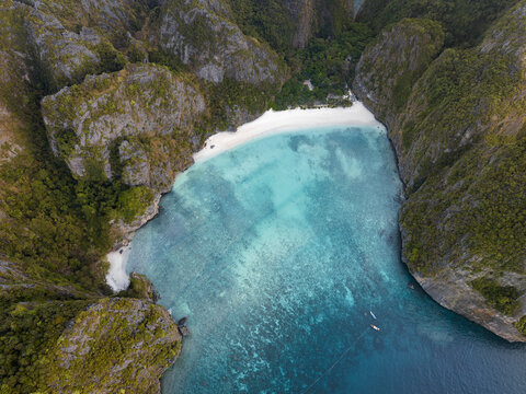 Aerial view of Phi Phi Islands featuring the turquoise waters of Maya Bay surrounded by steep limestone cliffs and lush vegetation in Mueang Krabi District, Krabi, Thailand.