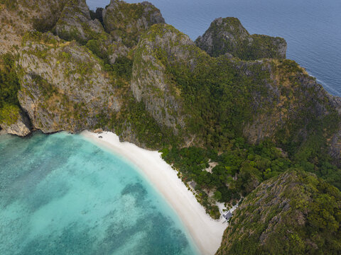 Aerial view of the white sand beach and turquoise waters of Phi Phi Islands surrounded by towering limestone cliffs and lush greenery in Mueang Krabi District, Krabi, Thailand.