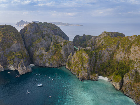 Aerial view of Phi Phi Islands with towering limestone cliffs, turquoise water and boats anchored near a beach Mueang Krabi District, Krabi, Thailand.
