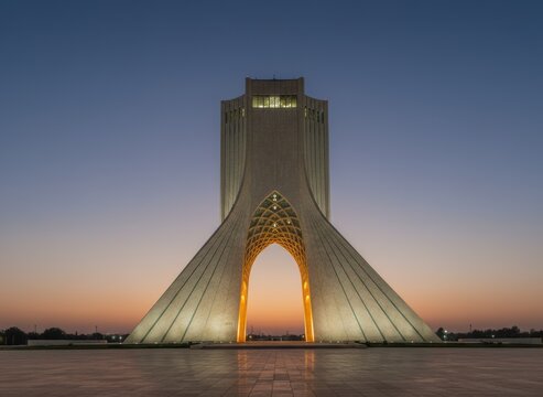 Azadi tower in tehran at twilight, illuminated monument with arched gateway