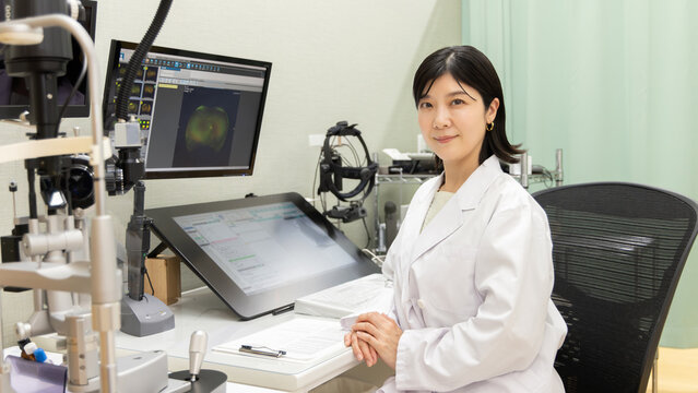 眼科クリニックで微笑む女性医師と最新検査機器のある診療室(モニターはテスト画面のはめ込み)