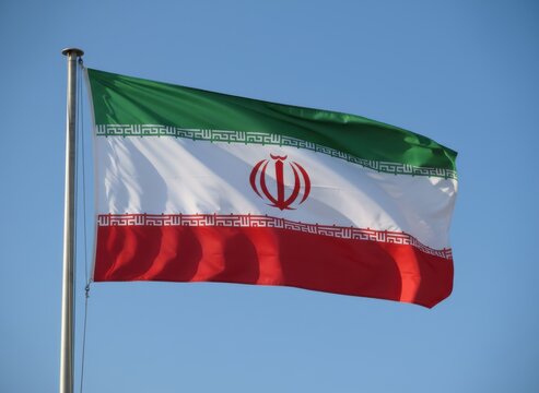 National flag of iran waving on a metal pole against a clear blue sky