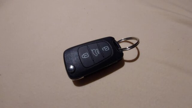 Hand placing a modern car remote key fob on a plain surface
