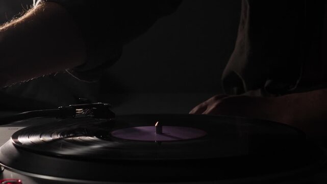 Dj hands manipulating vinyl on a professional turntable in a dark club, spinning and scratching records to mix beats and drive the live nightlife performance atmosphere