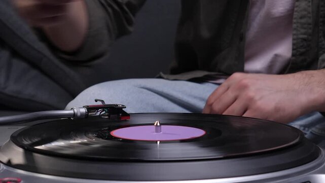 Person enjoying favorite songs, hand resting while a record spins on a modern turntable. Listening to retro music and relaxing in comfort with quality audio